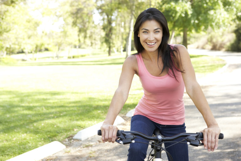 Young Woman Riding Bike In Park